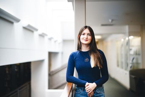 Jordan Ho stands for a portrait in Linderman library wearing a blue sweater.